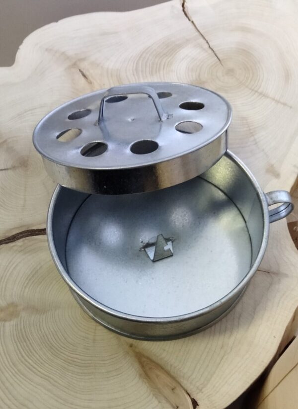 Kannellinen hyttyssavuastia, jossa on sisällä piikki savukierukkaa varten. Kannessa on reikiä. Kahva kannessa ja astian reunassa. Materiaali: galvanoitu pelti. Halkaisija 13 cm, korkeus 4,3 cm