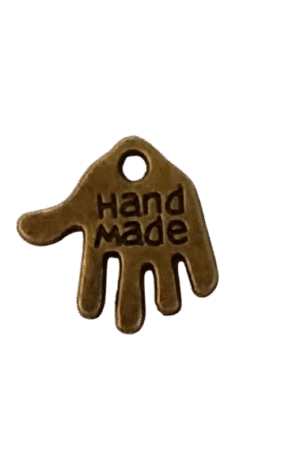 Kädenmallinen merkki, jossa on molemmpin puolin teksti "hand made". Merkin voi ommella kiinni esim. vaatteeseen. Merkki on kooltaan 1,8 x 1,8 cm. Väri: messinki.
