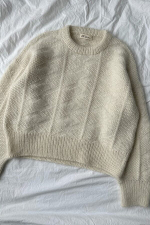 Luonnonvalkoinen PetiteKnit Esther Sweater -pusero tasolle levitettynä