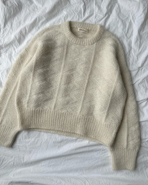 Luonnonvalkoinen PetiteKnit Esther Sweater -pusero tasolle levitettynä