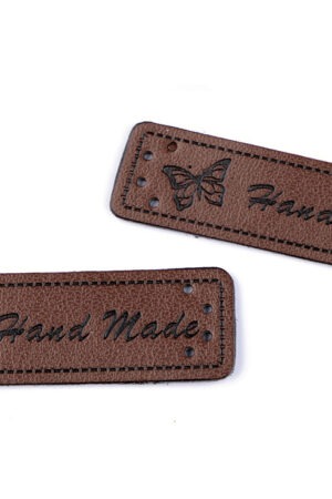 Tummanruskea hand made -merkki, suorakaide, vasemmassa reunassa perhosen kuva.