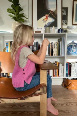 PetiteKnit Lulu Slipover Junior, lasten neuleliivi, mallin päällä, sivusta kuvattuna. Liivissä on nappikiinnitys molemmissa sivuissa.