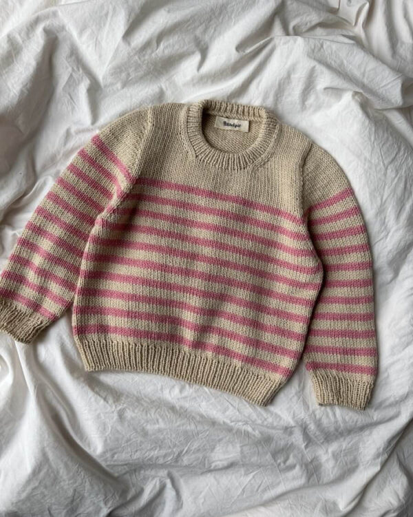 PetiteKnit Lyon Sweater Junior, tasolle levitettynä. Raidallinen lasten neulepusero, väreinä vaalea beige ja vaalenpunainen