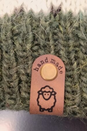 Handmade-merkki kiinnitettynä ruuvilla puseron helmassa. Kuviona on lammas.