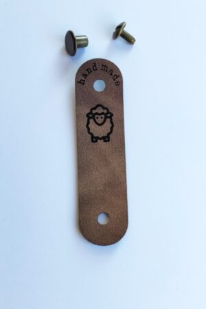 Handmade-merkki kiinnitettynä ruuvilla puseron helmassa. Kuviona on lammas.