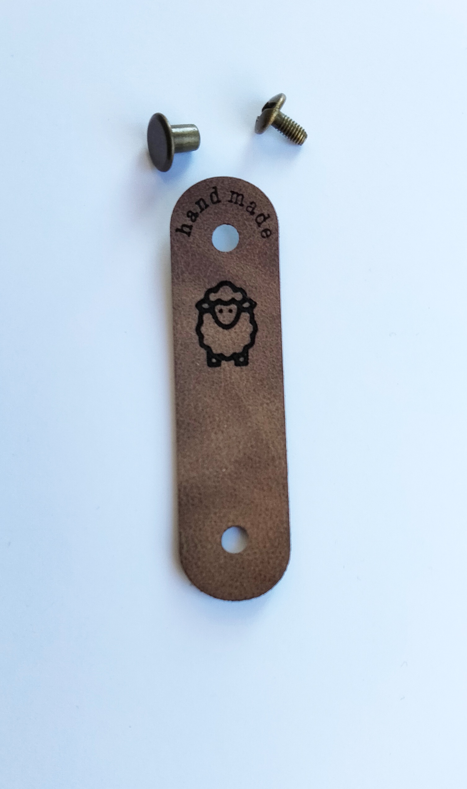 Handmade-merkki kiinnitettynä ruuvilla puseron helmassa. Kuviona on lammas.