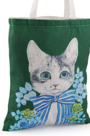 Puuvillakassin panatuksessa on vaalea kissa, jolla on suuri rusetti kaulassaan. Kuvituksena on lisäksi sinisiä kukkia. Tausta on vihreä.