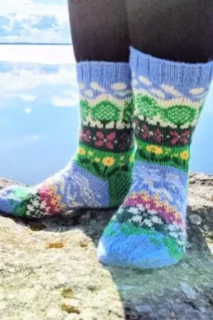 Kuvassa on kirjoneulesukat, joissa kuvioina on puita, kukkia ja virtaava vesi. Pääväri on helensininen.