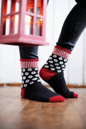 Kirjoneulesukat, joissa on mustalla pohjalla valkoisia pallokuvioita. Sukansuu, kantapää ja kärki ovat punaiset.