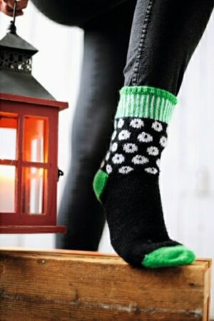 Kirjoneulesukat, joissa on mustalla pohjalla valkoisia palloja. Sukansuu, kantapää ja kärki ovat kirkkaanvihreät.